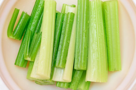 Fresh Chopped Celery Sticks with Water Drops in White Bowl - Top View. Vegan and Vegetarian Culture. Raw Food. Healthy Diet with Negative Calorie Content photo