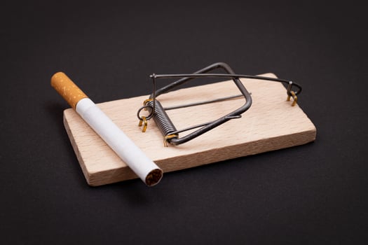 Tobacco Addiction and the World Corporation's Trap - Cigarettes in Wooden Mousetrap on Black Background photo