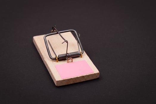 Blank Pink Sheet of Paper in Wooden Mousetrap - Template. Small Memo Paper in Mouse Trap on Black Background photo