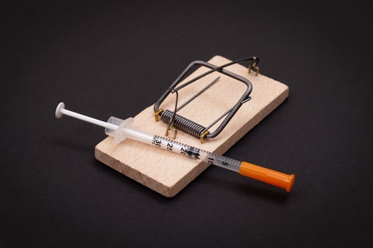 Drug Addict, Heroin Hazard or Dose Trap Concept - Disposable Insulin Syringe with Drug Dose Inside Lying in Wooden Mousetrap on Black Background photo