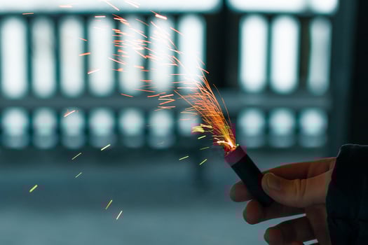 Burning Firecracker with Sparks. Guy Holding a Petard in a Hand. Loud and Dangerous New Year's Entertainment. Hooliganism with Pyrotechnics. Noise of Firecrackers in Public Places photo