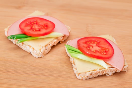 Rice Cake Sandwich with Tomato, Sausage, Green Onions and Cheese on Wooden Cutting Board. Easy Breakfast. Diet Food. Quick and Healthy Sandwiches. Crispbread with Tasty Filling. Healthy Dietary Snack photo