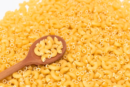 Uncooked Chifferi Rigati Pasta Background with Wooden Spoon. Fat and Unhealthy Food. Classic Dry Macaroni. Italian Culture and Cuisine. Raw Pasta photo