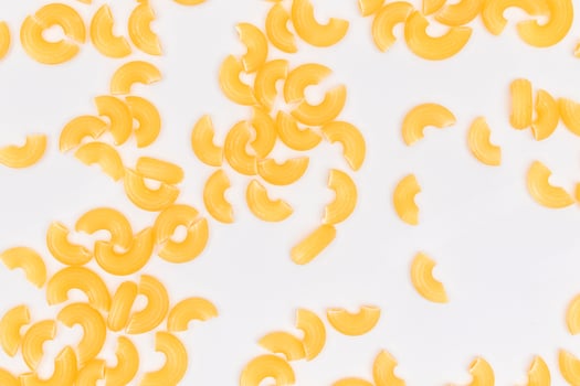 Scattered Uncooked Chifferi Rigati Pasta on White Background. Fat and Unhealthy Food. Classic Dry Macaroni Texture. Italian Culture and Cuisine. Raw Pasta photo
