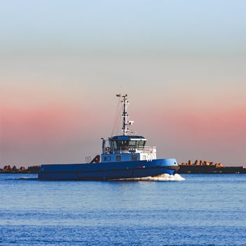 Blue small tug ship sailing past the breakwater dam in morning photo