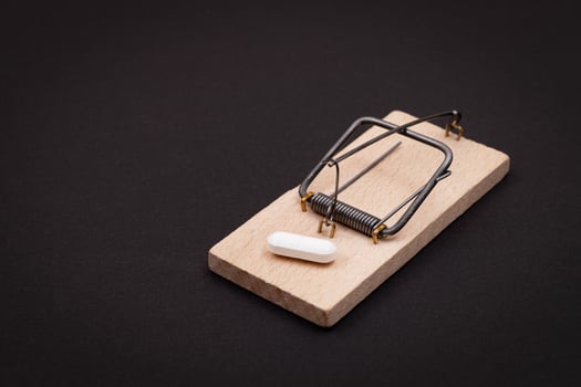 Pharmaceutical Addiction or Big Pharma Trap - White Pill in Wooden Mousetrap on Black Background photo