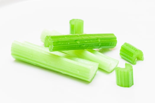 Fresh Chopped Celery Sticks and Slices with Water Drops Isolated on White Background. Vegan and Vegetarian Culture. Raw Food. Healthy Diet with Negative Calorie Content photo