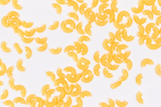 Scattered Uncooked Chifferi Rigati Pasta on White Background. Fat and Unhealthy Food. Classic Dry Macaroni Texture. Italian Culture and Cuisine. Raw Pasta photo