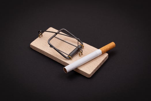 Tobacco Addiction and the World Corporation's Trap - Cigarettes in Wooden Mousetrap on Black Background photo