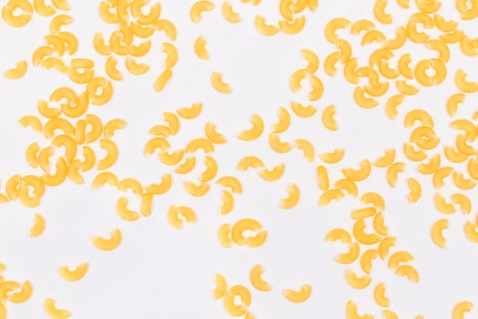 Scattered Uncooked Chifferi Rigati Pasta on White Background. Fat and Unhealthy Food. Classic Dry Macaroni Texture. Italian Culture and Cuisine. Raw Pasta photo