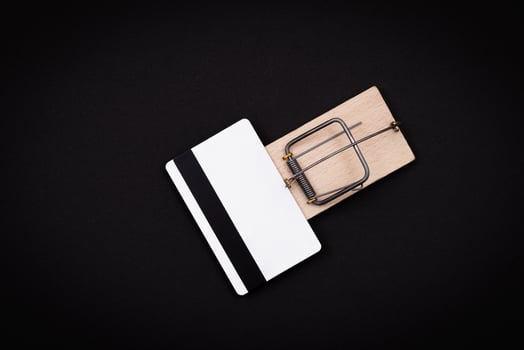 Credit Risk and Loan Trap - White Blank Credit Card Template in Wooden Mouse Trap on Black Background photo