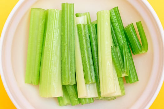 Fresh Chopped Celery Sticks with Water Drops in White Bowl - Top View. Vegan and Vegetarian Culture. Raw Food. Healthy Diet with Negative Calorie Content photo