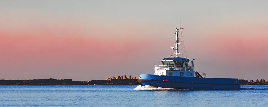 Blue small tug ship sailing past the breakwater dam in morning photo