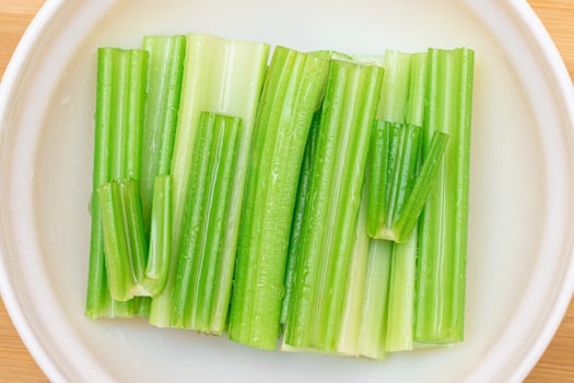 Fresh Chopped Celery Sticks with Water Drops in White Bowl - Top View. Vegan and Vegetarian Culture. Raw Food. Healthy Diet with Negative Calorie Content photo