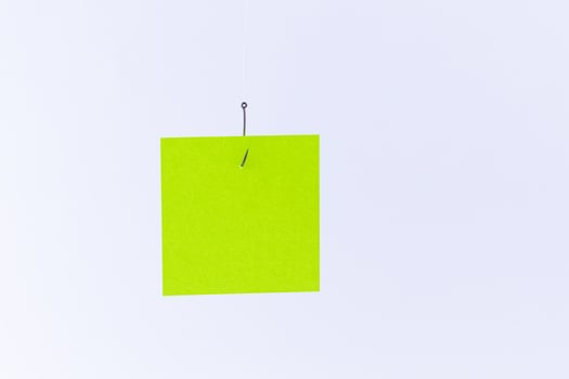 Mockup of a Blank Green Memo Paper with Copy Space Hanging on a Fishing Hook Against the White Background. Reminder or To Do List. Sticky Note Template photo