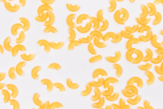 Scattered Uncooked Chifferi Rigati Pasta on White Background. Fat and Unhealthy Food. Classic Dry Macaroni Texture. Italian Culture and Cuisine. Raw Pasta photo