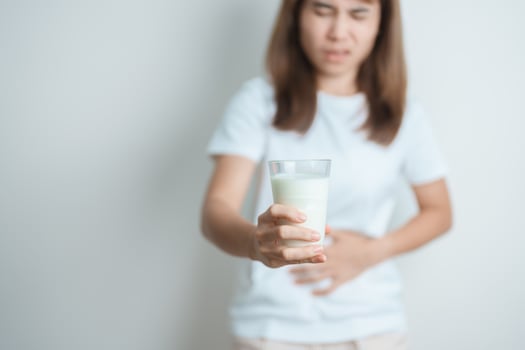 Lactose intolerance and Milk allergy concept. woman hold Milk glass and having abdominal cramps and pain when drink Cow Milk. Symptom stomach ache, Dairy intolerant, Nausea, Bloating, Gas and Diarrhea photo