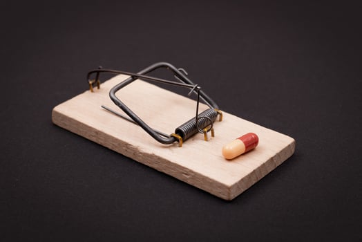 Pharmaceutical Addiction or Big Pharma Trap - Colored Pill or Capsule in Wooden Mousetrap on Black Background photo