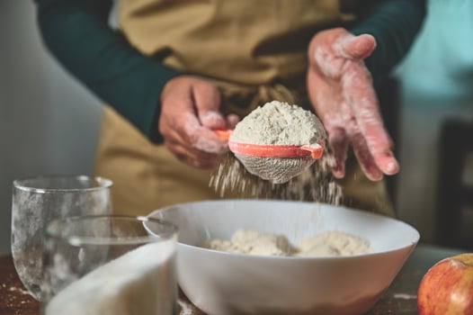 Close-up of hands sifting flour into a bowl, capturing the art of baking with focus on technique and texture photo