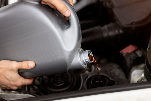 Mechanic pouring motor oil into engine for routine maintenance photo