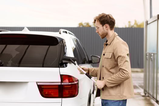 Stylish man cleaning car with squeegee at car wash photo