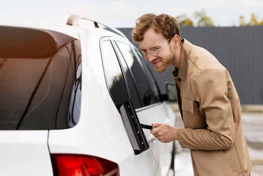 Mechanic cleaning car window with squeegee after washing it photo
