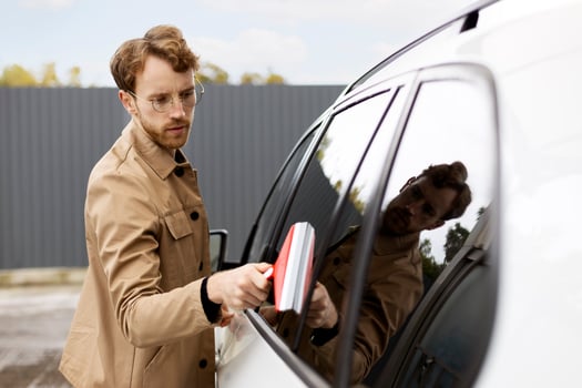 Young man cleaning his car with a squeegee outdoors photo