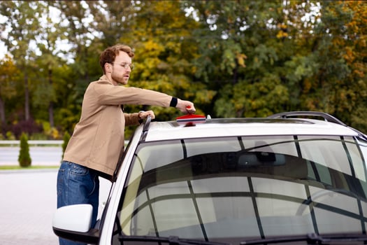 Young man cleaning his car roof with brush outdoors photo