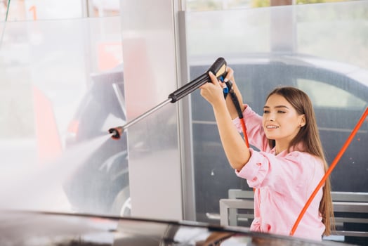 Young Woman Enjoying a Car Wash with High-Pressure Hose photo