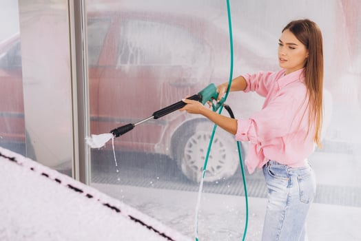 Young Woman Washing Car With High-Pressure Hose at Car Wash photo