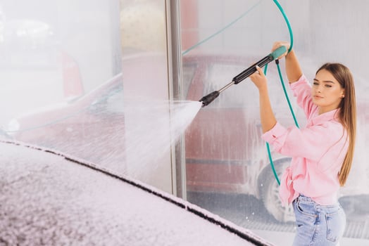 Young Woman Power Washing Car in Bright Pink Outfit photo