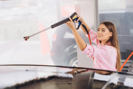 Young Woman Enjoying a Car Wash with High-Pressure Hose photo