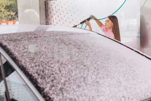 Young Woman Cleaning Car with Foam at Car Wash photo