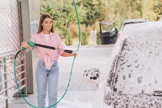 Young Woman Washing Car With High-Pressure Hose at Self-Service Station photo