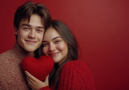 Couple smiling together while holding a heart shaped pillow in a cozy setting photo