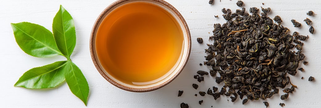 Freshly brewed tea in a cup next to loose tea leaves and green tea leaves on a wooden surface photo