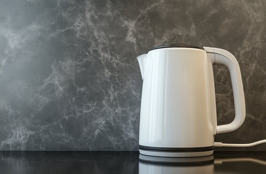 Modern white kettle on a kitchen counter against a textured gray background photo