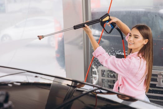Young Woman Smiling While Washing Her Car at Self-Service photo