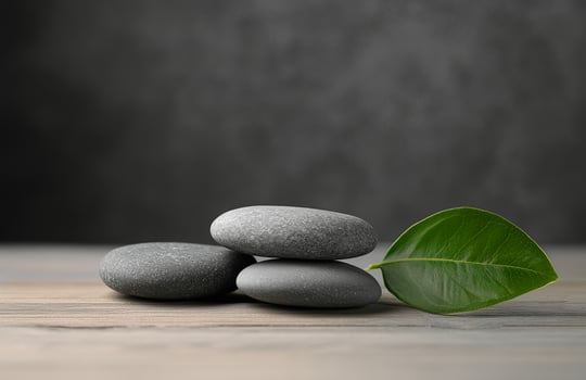 Relaxing stack of smooth stones with a green leaf on a wooden surface for wellness aesthetics photo