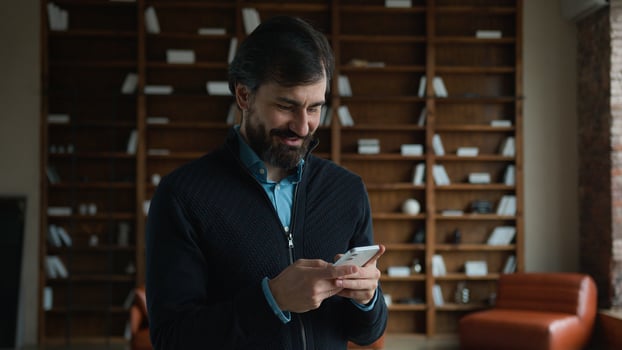 Laughing smiling Caucasian mature executive man business male employer boss having fun using mobile phone chatting app cellphone playing game browsing social media buying online ordering indoor office photo