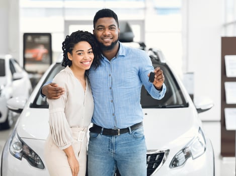 Joyful Black Couple Holding New Car Key Smiling At Camera Posing Standing Near Luxury Auto In Dealership Store photo