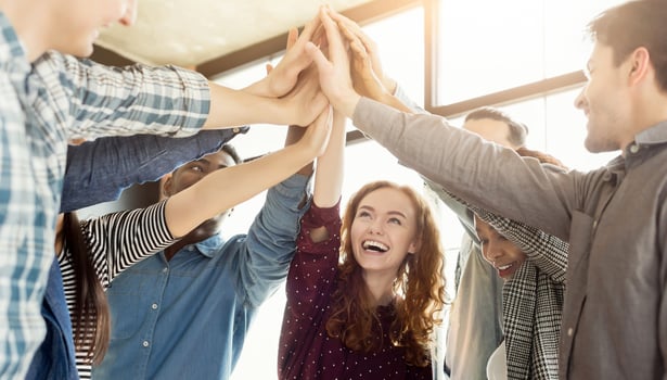 Teambuilding and unity background. Happy coworkers giving group high five in loft office, celebrating achievement photo