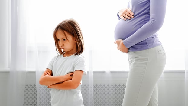 Sad little daughter turning from her pregnant mom belly, child crying for not wanting sibling, family issue, close up photo
