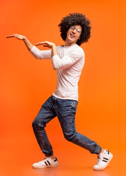 Funny black guy fooling, dancing in egypt style on orange studio background photo