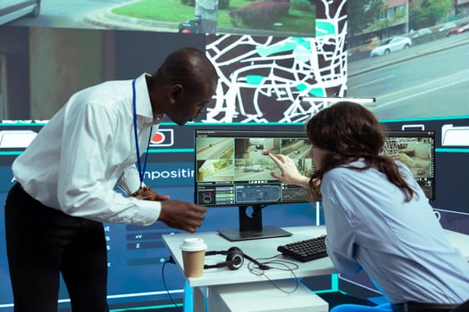 African american supervisor gives instructions to his staff in finding gps coordinates on satellite map, guiding couriers through CCTV surveillance footage. Order tracking and locating. photo