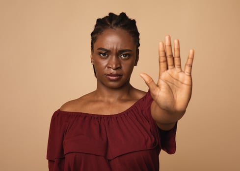 Young angry african american woman in casual outfit making the hand stop sign against beige studio background, closeup, copy space. Stop abuse, discrimination, violence concept photo