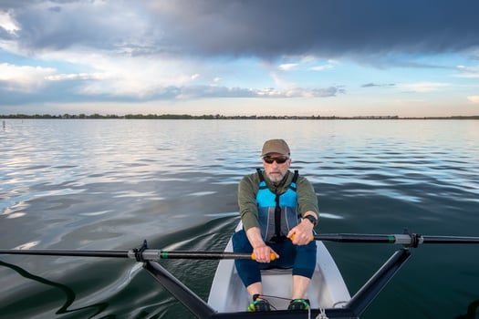 senior man in a rowing shell on a calm lake in Colorado photo