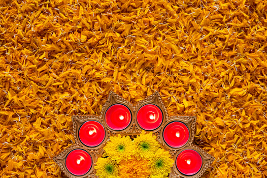 Decorative diya lamp lit with blurred focus flame for Diwali festival puts on orange marigold petals background. photo