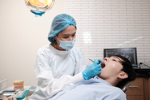 Asian female dentist examine young male patient teeth and toothache stomatology in dental clinic, well-being hygiene checks, and professional orthodontic healthcare work in doctor's office hospital. photo