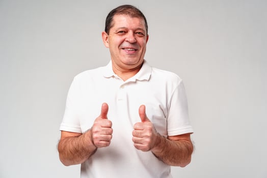 A cheerful middle-aged man giving double thumbs up against a plain background photo